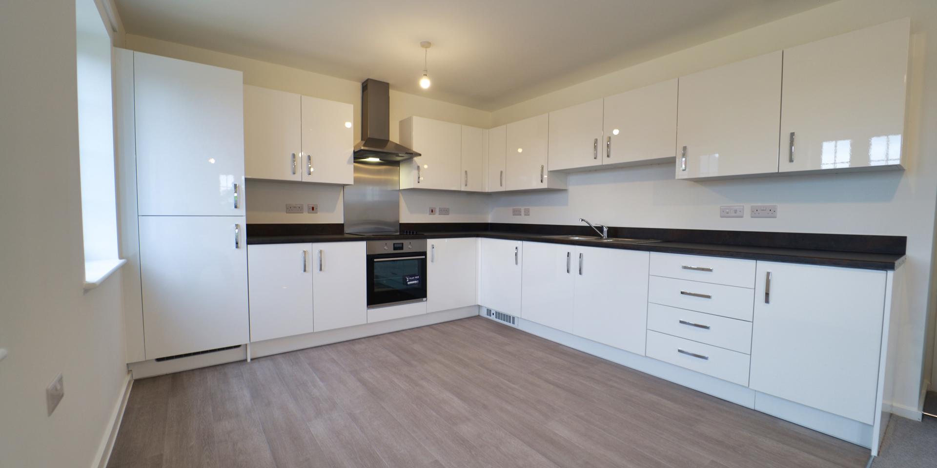 The kitchen is white gloss with chrome handles and black worktop. There are integrated appliances too.