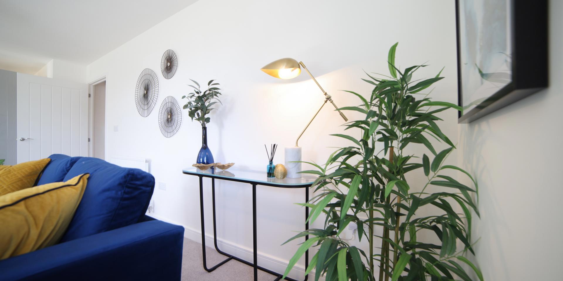 A console table in the living area with a lamp, vase and accessories on it.