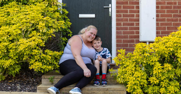 A mother and son sat outside of a house on the front doorstep. A mother and son sat outside of a house on the front doorstep.